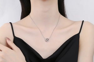 Close-up of a silver geometric circle and bead pendant on a delicate chain necklace