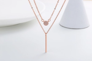 Close-up of double-layered rose gold necklace with circular pavé and bar pendants