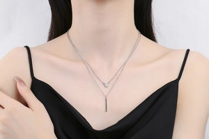 Close-up of double layer silver necklace with pavé diamond pendant and vertical bar on model
