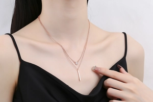 Macro view of double-layer rose gold necklace with zircon circle and vertical bar pendant