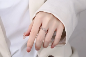 Gros plan d'une bague entrelacée en or rose avec pavé de pierres sur le doigt d'un mannequin