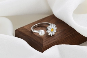 Detailed shot of spinning daisy ring with pearl accent on rustic wooden base