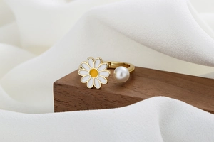 Detail of a rotating daisy flower ring with a white pearl on a gold adjustable band