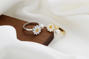 Detailed view of rotating daisy rings with white pearls and adjustable open bands