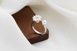 Detailed view of rotatable daisy flower and white pearl on silver open ring