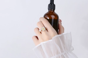 Detail of rotatable daisy flower and pearl on a golden adjustable open ring