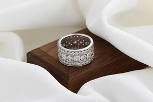 Macro shot of silver wide hollow ring with round and square cubic zirconia on wood