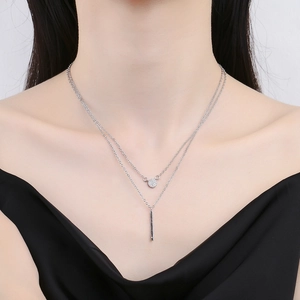 Double-layered silver necklace featuring a sparkling round pendant and vertical bar drop