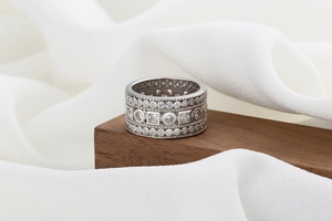 Detailed shot of a wide hip-hop silver ring with pavé cubic zirconia on wood