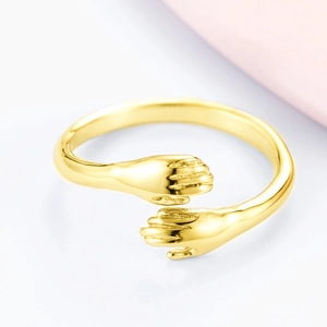 Macro shot of S925 silver hugging hands open ring with shiny gold-plated finish detail