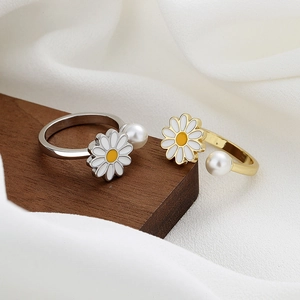 Adjustable daisy and pearl spinning ring in silver and gold on silk fabric background