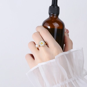 Rotating daisy flower and pearl open ring in gold finish on female finger