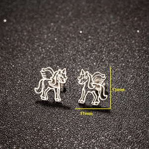 Moderne hohle Einhorn Ohrstecker aus Edelstahl für Damen auf dunklem Glitzerhintergrund