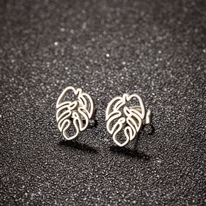 Macro detail of silver monstera leaf stud earrings on a textured black background