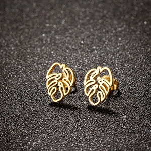 Golden monstera leaf stud earrings in polished stainless steel on a black background