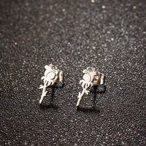 Macro shot of silver rose flower stud earrings with detailed leaves on black glitter background