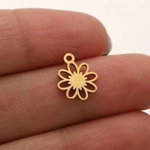 Vue détaillée d'un petit pendentif fleur évidé en acier plaqué or 18K tenu par les doigts