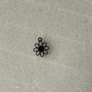 Gros plan d'un pendentif fleur ajouré noir avec bélière pour bijoux DIY