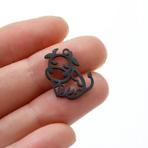 Détail macro d'un pendentif vache noir en acier inoxydable pour bijoux DIY entre les doigts
