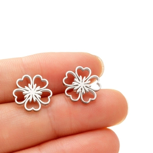 Boucles d'oreilles fleurs ajourées en acier inoxydable argenté posées sur un doigt