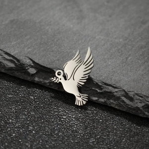 Detailed close-up of a silver dove pendant with olive branch on grey stone background