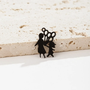 Detail of matte black silhouette charm showing a parent and child with five balloons