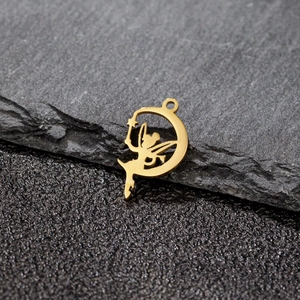 Vue macro d'un pendentif fée dorée évidée avec ailes assise sur un croissant de lune