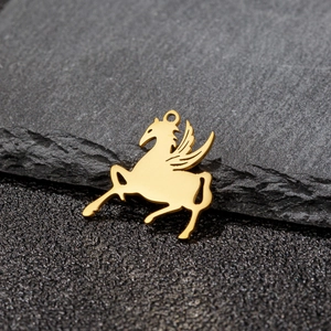 Macro detail of a golden Pegasus pendant with wings on a dark textured slate background