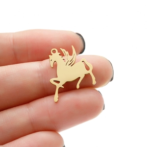 Detailed macro view of a golden Pegasus charm pendant held to show its actual small size