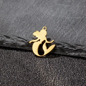 Gold stainless steel mermaid pendant with hollow silhouette on dark rock background