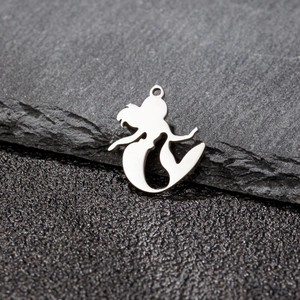 Detailed laser-cut stainless steel mermaid pendant charm on grey slate background