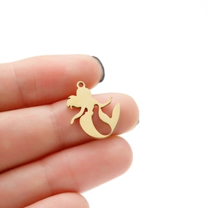 Close-up of a golden mermaid pendant in stainless steel held by hand for size reference