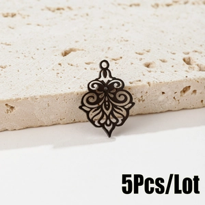Detailed view of 5pcs black stainless steel hollow flower charms on a stone background