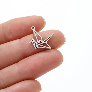 Vue détaillée d'un pendentif grue en origami en acier inoxydable sur le bout d'un doigt
