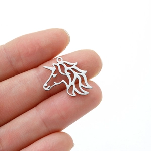 Close-up of a silver hollow unicorn charm held by fingers to show actual size for DIY jewelry