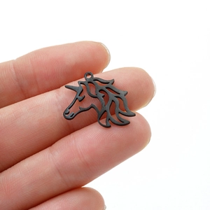 Macro detail of a laser-cut black unicorn pendant held to show small scale and texture