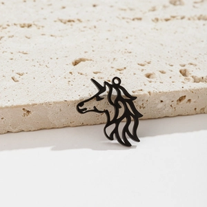 Detail of matte black unicorn pendant with cutout design on beige stone surface