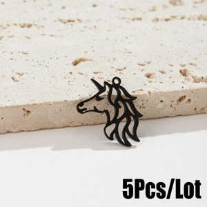 Macro shot of 5pcs matte black unicorn charms with cutout design on stone background