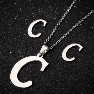 Macro view of polished stainless steel jewelry set with letter C pendant and studs