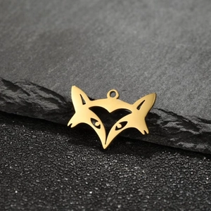 Minimalist golden fox head pendant in polished stainless steel on a dark stone background