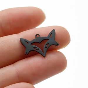 Detailed close-up of a black hollow fox head pendant charm held to show scale and matte finish