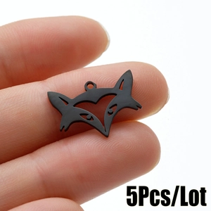 Macro shot of a matte black fox head pendant on fingertip showing its mini scale and loop
