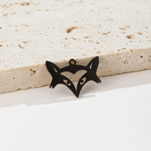 Close-up of a matte black fox head pendant with heart cutout on textured stone