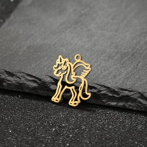 Golden hollowed unicorn pendant in 18k gold plated stainless steel on a stone texture