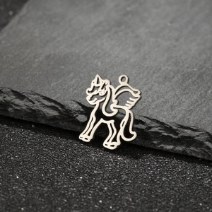 Polished stainless steel unicorn wing pendant on a textured dark stone background