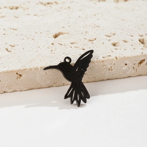 Vue détaillée d'un pendentif colibri noir mat sur une surface en pierre blanche