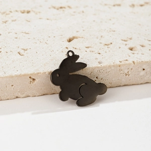 Detailed view of a black rabbit pendant accessory on a minimalist stone display stand