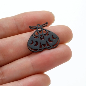 Macro shot of matte black moth charm with moon phase cutout and gothic style for DIY jewelry