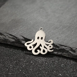 Macro detail of a polished stainless steel octopus pendant on a natural stone surface