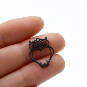Macro view of a matte black owl pendant with a hollow heart cutout for jewelry DIY